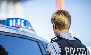 Eine Polizistin steht vor einem Streifenwagen, dessen Blaulicht leuchtet. Bei einem Einsatz in Gütersloh ist am Freitagabend eine Kommissarin schwer verletzt worden. - David Inderlied/dpa Eine Polizistin steht vor einem Streifenwagen, dessen Blaulicht leuchtet. Bei einem Einsatz in Gütersloh ist am Freitagabend eine Kommissarin schwer verletzt worden. - David Inderlied/dpa