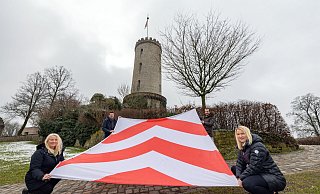 Stolze 3,50 mal 4,50 Meter ist die Sparrenburg-Flagge groß, die von Petra Löbbert (v.l.), Fabian Froböse, Julien Lienau und Deborah Becker gehalten wird. - Oliver Krato Stolze 3,50 mal 4,50 Meter ist die Sparrenburg-Flagge groß, die von Petra Löbbert (v.l.), Fabian Froböse, Julien Lienau und Deborah Becker gehalten wird. - Oliver Krato