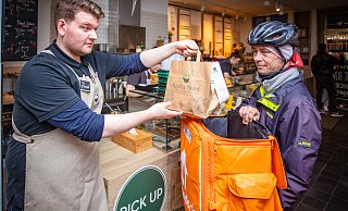 Daniel Götz von Dean and David stellt eine Tüte in den Rucksack von Lieferdienst-Fahrer Mirco Stellmach. - Mike-Dennis Müller / www.mdm.photo Daniel Götz von Dean and David stellt eine Tüte in den Rucksack von Lieferdienst-Fahrer Mirco Stellmach. - Mike-Dennis Müller / www.mdm.photo