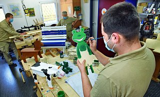Kevin (im Vordergrund), Jörg (hinten links) und ein weiterer Gefangener der JVA Bielefeld-Brackwede fertigen Holzfiguren. Die werden dann bei knastladen.de verkauft. Der grüne Frosch im Vordergrund bekommt noch einen Schirm. - Barbara Franke Kevin (im Vordergrund), Jörg (hinten links) und ein weiterer Gefangener der JVA Bielefeld-Brackwede fertigen Holzfiguren. Die werden dann bei knastladen.de verkauft. Der grüne Frosch im Vordergrund bekommt noch einen Schirm. - Barbara Franke