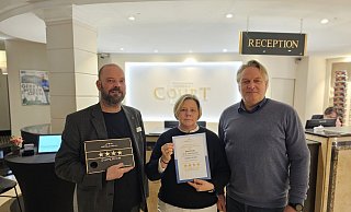 Hoteldirektor Sebastian Flaith (l.) präsentiert die Plakette mit der neuen Zertifizierung des Court Hotels, die er von Andrea Windmann und Detlef Rübenach erhalten hat. - Court Hotel Hoteldirektor Sebastian Flaith (l.) präsentiert die Plakette mit der neuen Zertifizierung des Court Hotels, die er von Andrea Windmann und Detlef Rübenach erhalten hat. - Court Hotel