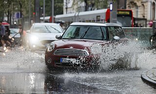 Ein Auto fährt während eines Gewitters im Regen durch eine Pfütze. - Oliver Berg/dpa Ein Auto fährt während eines Gewitters im Regen durch eine Pfütze. - Oliver Berg/dpa