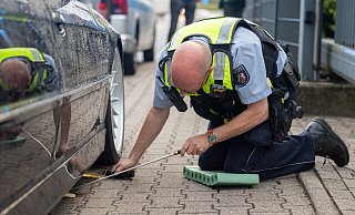 Ein Polizist kontrolliert die Bodenfreiheit eines vermeintlich zu tiefen 7er-BMW. Sie ist ausreichend: Der BMW darf weiterfahren. - Oliver Krato Ein Polizist kontrolliert die Bodenfreiheit eines vermeintlich zu tiefen 7er-BMW. Sie ist ausreichend: Der BMW darf weiterfahren. - Oliver Krato