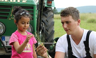 Landwirt Timo zeigt Lily die Grannen an der Getreideähre. Beim Bauernhof-Erlebnistag wird ein vielfältiges Programm mit Aktionen, Informationen und Köstlichem für die Großen unddie Kleinen geboten. - WLV Landwirt Timo zeigt Lily die Grannen an der Getreideähre. Beim Bauernhof-Erlebnistag wird ein vielfältiges Programm mit Aktionen, Informationen und Köstlichem für die Großen unddie Kleinen geboten. - WLV
