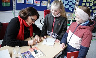 Kinderbuchautorin Julia Boehme schreibt nach der Lesung in der Turnhalle für Lina und Xenia Autogramme. - Dieter Scholz Kinderbuchautorin Julia Boehme schreibt nach der Lesung in der Turnhalle für Lina und Xenia Autogramme. - Dieter Scholz