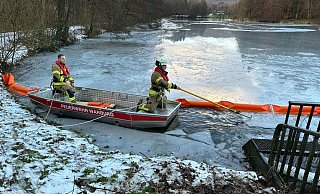 Aus dem Boot heraus bringen Einsatzkräft der Warburger Feuerwehr eine Ölsperre am Überlauf des Korintenteichs in Hardehausen an. - FFW Warburg Aus dem Boot heraus bringen Einsatzkräft der Warburger Feuerwehr eine Ölsperre am Überlauf des Korintenteichs in Hardehausen an. - FFW Warburg