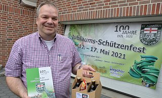 Frank Hachmann mit der Chronik der St.-Achatius-Schützenbruderschaft und dem „Trostpaket“ als Ersatz für das ausgefallene Jubiläumsschützenfest, auf das der Aufdruck auf dem Banner hinweist. - Karin Prignitz Frank Hachmann mit der Chronik der St.-Achatius-Schützenbruderschaft und dem „Trostpaket“ als Ersatz für das ausgefallene Jubiläumsschützenfest, auf das der Aufdruck auf dem Banner hinweist. - Karin Prignitz