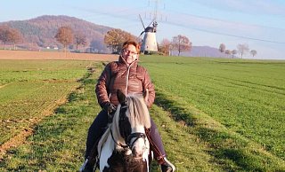 Brunhild Homann bei einem Ausritt auf ihrem Pferd. Die Holländerwindmühle Struckhof im Hintergrund ist namensgebend für den Schnathorster Ortsteil. - Brunhild Homann Brunhild Homann bei einem Ausritt auf ihrem Pferd. Die Holländerwindmühle Struckhof im Hintergrund ist namensgebend für den Schnathorster Ortsteil. - Brunhild Homann