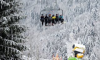 Skifahrer fahren in Winterberg bei winterlichem Wetter in einem Sessellift an einer Schneekanone vorbei. - Bernd Thissen Skifahrer fahren in Winterberg bei winterlichem Wetter in einem Sessellift an einer Schneekanone vorbei. - Bernd Thissen