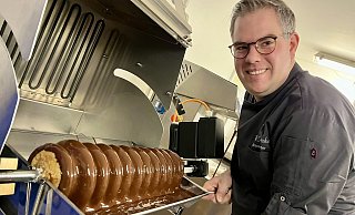 Die Baumkuchenmaschine war eine große Anschaffung für den Chocolatier. Patrick Dreker produziert damit Variationen in diversen Schokoüberzügen und Größen. Viele Kunden kennen die Leckerei nur noch aus der industriellen Produktion. Die Herstellung ist aufwendig, weil bis zu 20 Teigschichten zügig aufgebracht werden müssen. - Jens Reddeker Die Baumkuchenmaschine war eine große Anschaffung für den Chocolatier. Patrick Dreker produziert damit Variationen in diversen Schokoüberzügen und Größen. Viele Kunden kennen die Leckerei nur noch aus der industriellen Produktion. Die Herstellung ist aufwendig, weil bis zu 20 Teigschichten zügig aufgebracht werden müssen. - Jens Reddeker