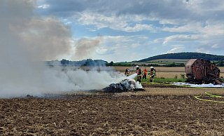 Nach der Rundballenpresse (r.) musste auch noch gepresstes brennendes Stroh gelöscht werden. - FFW Warburg Nach der Rundballenpresse (r.) musste auch noch gepresstes brennendes Stroh gelöscht werden. - FFW Warburg