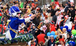 Ein Karnevalist wirft an Rosenmontag in Köln von einem Mottowagen Süßigkeiten ins Publikum. - Oliver Berg Ein Karnevalist wirft an Rosenmontag in Köln von einem Mottowagen Süßigkeiten ins Publikum. - Oliver Berg