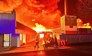 Im roten Feuerschein bringen Ulf Nabers (l.) und Bastian Bröckelmann in Rheda-Wiedenbrück im Kreis Gütersloh eine Palette mit Gasflaschen am 11. Februar aus der Gefahrenzone. - Thorsten Heß Im roten Feuerschein bringen Ulf Nabers (l.) und Bastian Bröckelmann in Rheda-Wiedenbrück im Kreis Gütersloh eine Palette mit Gasflaschen am 11. Februar aus der Gefahrenzone. - Thorsten Heß