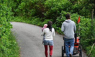Ein Paar mit Kind läuft eine schmale Straße entlang. Die aktuelle Elterngeld-Debatte trifft viele Familien. - picture alliance/dpa Ein Paar mit Kind läuft eine schmale Straße entlang. Die aktuelle Elterngeld-Debatte trifft viele Familien. - picture alliance/dpa
