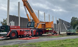 Ein großer Autokran platziert die Dämmplatten zwischen die mit Nuten versehenen Pfosten. Rechts sind die Wände bereits fertiggestellt. - Markus Voss Ein großer Autokran platziert die Dämmplatten zwischen die mit Nuten versehenen Pfosten. Rechts sind die Wände bereits fertiggestellt. - Markus Voss