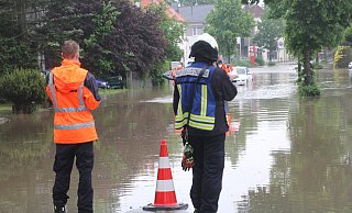 Feuerwehrleute sperren eine überflutete Straße in Bünde ab. - Florian Weyand Feuerwehrleute sperren eine überflutete Straße in Bünde ab. - Florian Weyand
