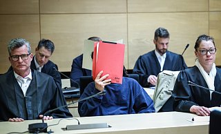 Prozess im Mai 2023: Einer der Angeklagten versteckt sein Gesicht hinter einem roten Aktendeckel. Er wird von den Strafverteidigern Detlev Binder (l.) und Susanne Renner vertreten. Hinter ihnen sitzt der zweite Angeklagte, der ebenfalls unerkannt bleiben will. Sie sollen einen Mann aus einem Flüchtlingsheim in Spenge entführt haben. - Sarah Jonek Prozess im Mai 2023: Einer der Angeklagten versteckt sein Gesicht hinter einem roten Aktendeckel. Er wird von den Strafverteidigern Detlev Binder (l.) und Susanne Renner vertreten. Hinter ihnen sitzt der zweite Angeklagte, der ebenfalls unerkannt bleiben will. Sie sollen einen Mann aus einem Flüchtlingsheim in Spenge entführt haben. - Sarah Jonek