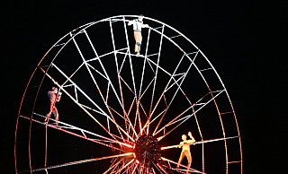 Die Akrobatinnen und Akrobaten zeigen auf dem Riesenrad ihr Können. Sie scheuen sich dabei auch nicht, komplett in den See unter ihnen abzutauchen. - Thomas Kube Die Akrobatinnen und Akrobaten zeigen auf dem Riesenrad ihr Können. Sie scheuen sich dabei auch nicht, komplett in den See unter ihnen abzutauchen. - Thomas Kube