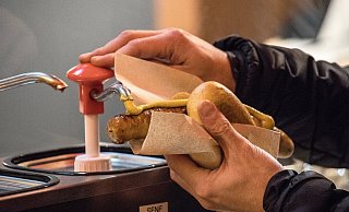 Ein Mann pumpt Senf auf eine Bratwurst im Brötchen. - dpa Ein Mann pumpt Senf auf eine Bratwurst im Brötchen. - dpa