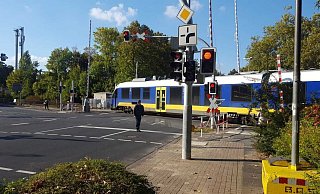 Der Zug überquert den Bahnübergang, obwohl die Schranken geöffnet sind. Ein Fußgänger beobachtet mitten auf der Fahrbahn stehend diese Situation. - Wolfgang Döbber Der Zug überquert den Bahnübergang, obwohl die Schranken geöffnet sind. Ein Fußgänger beobachtet mitten auf der Fahrbahn stehend diese Situation. - Wolfgang Döbber
