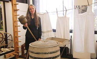 Museumsleiterin Sonja Voss in dem Bereich der Ausstellung, der sich mit dem Thema Waschen beschäftigt. In der Hand hält sie eine Waschglocke, vor ihr steht eine alte Waschmaschine. - Anthea Moschner Museumsleiterin Sonja Voss in dem Bereich der Ausstellung, der sich mit dem Thema Waschen beschäftigt. In der Hand hält sie eine Waschglocke, vor ihr steht eine alte Waschmaschine. - Anthea Moschner