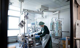 Eine Pflegekraft steht in einem Zimmer der Corona-Intensivstation und behandelt einen Patienten. - Fabian Strauch Eine Pflegekraft steht in einem Zimmer der Corona-Intensivstation und behandelt einen Patienten. - Fabian Strauch