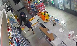 Auf dem Überwachungsvideo ist zu sehen, wie ein vermummter Mann eine Flüssigkeit - vermutlich Brandbeschleuniger - verspritzt. - Polizei/Screenshot Auf dem Überwachungsvideo ist zu sehen, wie ein vermummter Mann eine Flüssigkeit - vermutlich Brandbeschleuniger - verspritzt. - Polizei/Screenshot
