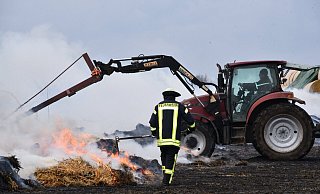 Mit Treckern wurde am Sonntagmittag begonnen, das Stroh auseinander zu ziehen. Foto: Thomas Kube - Thomas Kube Mit Treckern wurde am Sonntagmittag begonnen, das Stroh auseinander zu ziehen. Foto: Thomas Kube - Thomas Kube