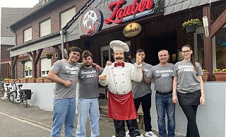 Renas Anit (v.l.), Fahrer Robin Schiefelbein, Ronijan Anit, Chef Cindo Anit und Bedienung Beste Sez vor dem "Zaubertopf" im Greffener Ortskern. - Markus Voss Renas Anit (v.l.), Fahrer Robin Schiefelbein, Ronijan Anit, Chef Cindo Anit und Bedienung Beste Sez vor dem "Zaubertopf" im Greffener Ortskern. - Markus Voss