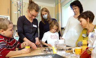 Ergotherapeutin Vera Gans (2.v.l.) und Musiktherapeutin Annette Gehler (r.) backen mit betroffenen Familien zu Weihnachten. - HandanHand Ergotherapeutin Vera Gans (2.v.l.) und Musiktherapeutin Annette Gehler (r.) backen mit betroffenen Familien zu Weihnachten. - HandanHand
