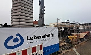 Am Bauzaun ist das Logo der Lebenshilfe zu sehen. Links hinter dem Neubau liegt die Wohnstätte direkt auf dem Nachbargrundstück. - Simone Flörke Am Bauzaun ist das Logo der Lebenshilfe zu sehen. Links hinter dem Neubau liegt die Wohnstätte direkt auf dem Nachbargrundstück. - Simone Flörke