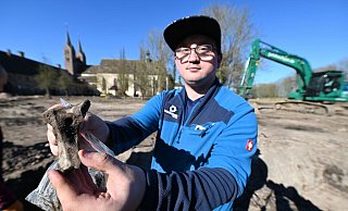 Grabungshelfer Dominik Schröder mit einem menschlichen Schenkelhalsknochen. Auf dem Gelände haben Experten mehrere Gräber entdeckt. - Thomas Kube Grabungshelfer Dominik Schröder mit einem menschlichen Schenkelhalsknochen. Auf dem Gelände haben Experten mehrere Gräber entdeckt. - Thomas Kube