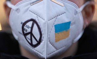Eine Frau trägt während einer Demonstration eine FFP2-Maske, auf die das Peace-Zeichen und die ukrainische Fahne gemalt sind. Tatsächlich hat der Krieg in Osteuropa Auswirkungen auf die Corona-Situation in Deutschland. - AFP or licensors Eine Frau trägt während einer Demonstration eine FFP2-Maske, auf die das Peace-Zeichen und die ukrainische Fahne gemalt sind. Tatsächlich hat der Krieg in Osteuropa Auswirkungen auf die Corona-Situation in Deutschland. - AFP or licensors