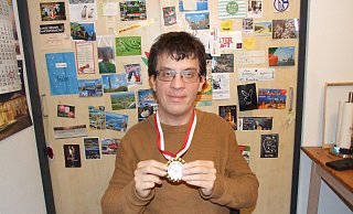 Benjamin Estermann präsentiert in seiner Wohnung die Goldmedaille. Er steht vor einer Wand, die mit Ansichtskarten beklebt ist, die aus der ganzen Welt stammen. Es sind Grüße von Tanzfreunden, mit denen Estermann in ständigem Kontakt steht. - Karsten Schulz Benjamin Estermann präsentiert in seiner Wohnung die Goldmedaille. Er steht vor einer Wand, die mit Ansichtskarten beklebt ist, die aus der ganzen Welt stammen. Es sind Grüße von Tanzfreunden, mit denen Estermann in ständigem Kontakt steht. - Karsten Schulz