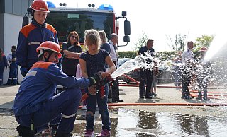 Die Helfer von der Jugendfeuerwehr zeigen den Jüngsten wie sie den Schlauch festhalten. Hier probiert sich Clara aus. - Yvonne Gottschlich Die Helfer von der Jugendfeuerwehr zeigen den Jüngsten wie sie den Schlauch festhalten. Hier probiert sich Clara aus. - Yvonne Gottschlich