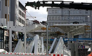 Zwar verzögert – aber der Aufbau der Haltestellendächer auf dem Jahnplatz geht weiter. Jetzt steht auch das erste der höheren vorderen Dächer, die über die Einstiegskante ragen. Ein Kran hebt die Dreiecke an, aus denen die Dächer zusammengesetzt sind. - Wolfgang Rudolf Zwar verzögert – aber der Aufbau der Haltestellendächer auf dem Jahnplatz geht weiter. Jetzt steht auch das erste der höheren vorderen Dächer, die über die Einstiegskante ragen. Ein Kran hebt die Dreiecke an, aus denen die Dächer zusammengesetzt sind. - Wolfgang Rudolf