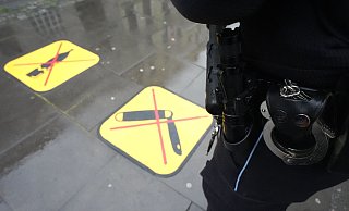 Eine Polizistin steht neben zwei Piktogrammen zum Glasflaschen- und Waffenverbot. - Marcus Brandt/dpa Eine Polizistin steht neben zwei Piktogrammen zum Glasflaschen- und Waffenverbot. - Marcus Brandt/dpa