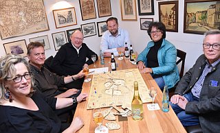 LGS-Logo-Designerin Barbara Fien (v. l.), Hans-Peter Rohler (TH OWL), Heinrich Sperling (LGS-Geschäftsführer), Heiko Böddeker (Gesellschaft für Wirtschaftsförderung im Kreis Höxter), Claudia Koch (LGS-Geschäftsführerin) und Michael Rindermann (Corveyer Weinhaus) spielen in den Bürgerstuben das Landesgartenschau-Spiel. - LGS LGS-Logo-Designerin Barbara Fien (v. l.), Hans-Peter Rohler (TH OWL), Heinrich Sperling (LGS-Geschäftsführer), Heiko Böddeker (Gesellschaft für Wirtschaftsförderung im Kreis Höxter), Claudia Koch (LGS-Geschäftsführerin) und Michael Rindermann (Corveyer Weinhaus) spielen in den Bürgerstuben das Landesgartenschau-Spiel. - LGS