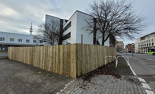Ein zwei Meter hoher Bretterzaun kündigt den Start der Arbeiten auf dem Postareal an. - Ludger Osterkamp Ein zwei Meter hoher Bretterzaun kündigt den Start der Arbeiten auf dem Postareal an. - Ludger Osterkamp