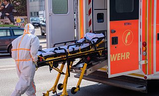 Infektionstransport: Ein Notfallsanitäter in Schutzkleidung schiebt die Trage zurück in den Rettungswagen, in dem zuvor eine infizierte Person transportiert wurde. - Christian Mathiesen Infektionstransport: Ein Notfallsanitäter in Schutzkleidung schiebt die Trage zurück in den Rettungswagen, in dem zuvor eine infizierte Person transportiert wurde. - Christian Mathiesen