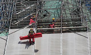 Ende 2018 simulieren die Höhenretter das Abseilen eines verletzten Arbeiters vom Gerüst, das damals noch den Turm einhüllt. - Marco Schreiber Ende 2018 simulieren die Höhenretter das Abseilen eines verletzten Arbeiters vom Gerüst, das damals noch den Turm einhüllt. - Marco Schreiber