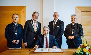 Vor seiner Festrede trägt sich Stephan Harbarth, Präsident des Bundesverfassungsgerichts, ins Goldene Buch der Stadt Paderborn ein. Hinter ihm stehen Jean-Pierre Vuillemin Bischof von Le Mans (v. l.), Bürgermeister Michael Dreier, Gildemeister Johannes Beverungen und Erzbischof Udo Markus Bentz. - Besim Mazhiqi Vor seiner Festrede trägt sich Stephan Harbarth, Präsident des Bundesverfassungsgerichts, ins Goldene Buch der Stadt Paderborn ein. Hinter ihm stehen Jean-Pierre Vuillemin Bischof von Le Mans (v. l.), Bürgermeister Michael Dreier, Gildemeister Johannes Beverungen und Erzbischof Udo Markus Bentz. - Besim Mazhiqi