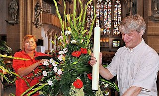 Floristin Bärbel Sporkmann legt a einem der vielen Gestecke im Altarraum letzte Hand an. Küster Robert Schäfers steckt eine Kerze in den dafür vorgesehenden Ständer.Libori kann kommen. - FOTO: REINHARD ROHLF Floristin Bärbel Sporkmann legt a einem der vielen Gestecke im Altarraum letzte Hand an. Küster Robert Schäfers steckt eine Kerze in den dafür vorgesehenden Ständer.Libori kann kommen. - FOTO: REINHARD ROHLF