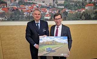 Ein Geschenk für das Stadthaus als Zeichen für die gute Zusammenarbeit: Georg Arendes, Leiter der Polizeiwache Warburg, übergab Bürgermeister Tobias Scherf ein Bild, das ein Fahrzeug der Polizei vor dem Desenberg zeigt. - Stadt Warburg Ein Geschenk für das Stadthaus als Zeichen für die gute Zusammenarbeit: Georg Arendes, Leiter der Polizeiwache Warburg, übergab Bürgermeister Tobias Scherf ein Bild, das ein Fahrzeug der Polizei vor dem Desenberg zeigt. - Stadt Warburg