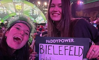 Mia (l.) und Ella Henrichsmeyer halten bei der Darts-WM im Ally Pally in London die Bielefelder Fahne hoch. - Henrichsmeyer Mia (l.) und Ella Henrichsmeyer halten bei der Darts-WM im Ally Pally in London die Bielefelder Fahne hoch. - Henrichsmeyer