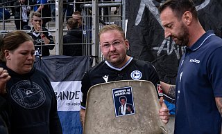 12.09.2025, Fussball, 2.Liga, Saison 2025/2026, DSC Arminia Bielefeld - 1. FC Magdeburg, Ben Ollick und seine Familie bekommen die Sitzschale seines verstorbenen Vaters von Trainer Mitch Kniat (Arminia Bielefeld) überreicht.Foto: Teresa Kroeger - Teresa Kroeger 12.09.2025, Fussball, 2.Liga, Saison 2025/2026, DSC Arminia Bielefeld - 1. FC Magdeburg, Ben Ollick und seine Familie bekommen die Sitzschale seines verstorbenen Vaters von Trainer Mitch Kniat (Arminia Bielefeld) überreicht.Foto: Teresa Kroeger - Teresa Kroeger