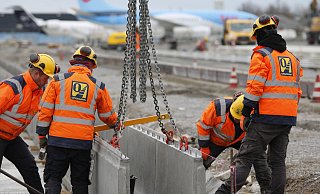 Bauarbeiter setzen momentan Betonrinnen auf das Fundament. Diese sollen später Niederschläge wie Regenwasser abführen. Zudem wird auf einer Fläche von 15.000 Quadrametern neuer Beton eingelassen. - David Knapp Bauarbeiter setzen momentan Betonrinnen auf das Fundament. Diese sollen später Niederschläge wie Regenwasser abführen. Zudem wird auf einer Fläche von 15.000 Quadrametern neuer Beton eingelassen. - David Knapp