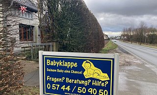 Ein Schild weist an der Hüllhorster Hauptstraße auf den Standort der Babyklappe hin. Der Eingang befindet abgeschirmt von einer hohen Hecke direkt rechts hinter dem Tor am Haus. - Kirsten Tirre Ein Schild weist an der Hüllhorster Hauptstraße auf den Standort der Babyklappe hin. Der Eingang befindet abgeschirmt von einer hohen Hecke direkt rechts hinter dem Tor am Haus. - Kirsten Tirre
