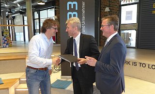 Grund zur Freude: Bürgermeister Michael Dreier (r.) und Uni-Vizepräsident Rüdiger Kabst (l.) erhielten von Minister Andreas Pinkwart den in eine schwarze Kladde verpackten Förderbescheid für Garage 33. - Hans-Hermann Igges Grund zur Freude: Bürgermeister Michael Dreier (r.) und Uni-Vizepräsident Rüdiger Kabst (l.) erhielten von Minister Andreas Pinkwart den in eine schwarze Kladde verpackten Förderbescheid für Garage 33. - Hans-Hermann Igges