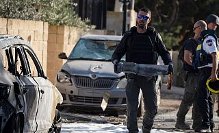 Ein Mitglied der israelischen Sicherheitskräfte trägt ein Stück eines Geschosses, das vom Libanon aus auf Nahariya abgefeuert wurde. - Leo Correa/AP Ein Mitglied der israelischen Sicherheitskräfte trägt ein Stück eines Geschosses, das vom Libanon aus auf Nahariya abgefeuert wurde. - Leo Correa/AP